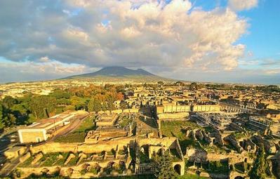 Pompeii with Mount Vesuvius in the background (photo by ElfQrin, https://pt.wikipedia.org/wiki/Ficheiro:Ruins_of_Pompeii_with_the_Vesuvius.jpg / CC-BY-SA 4.0)